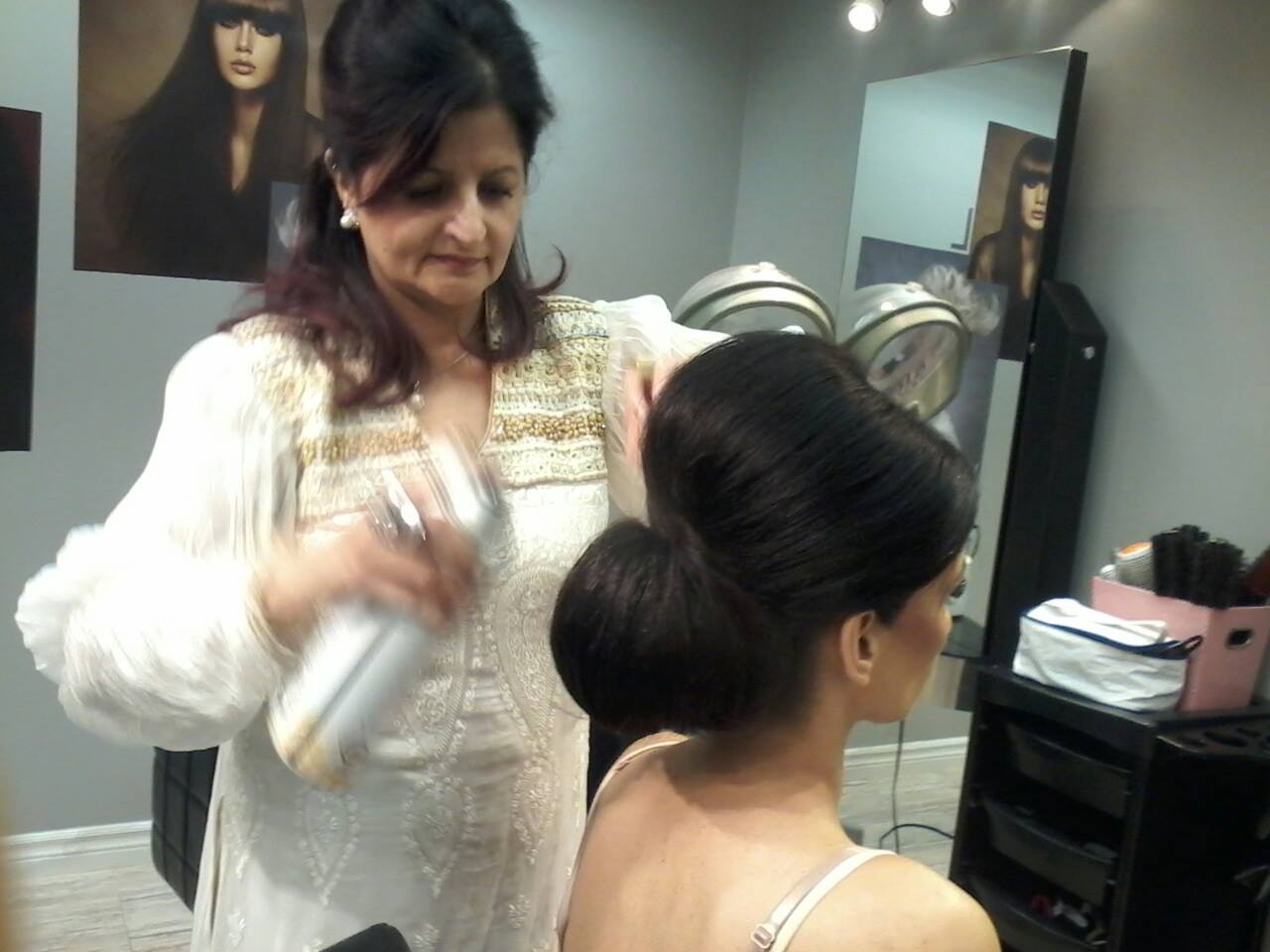 Gul finishing a sleek updo with hairspray at her salon studio