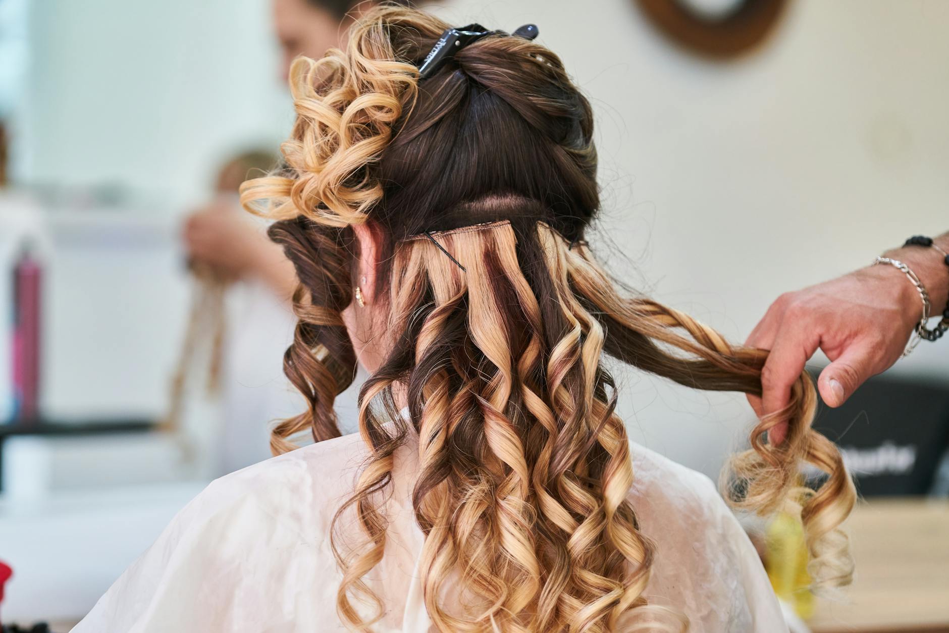 Close-up of a hairstylist perfecting curls on a woman's hair in a salon setting